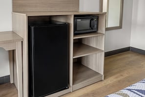 A kitchen with a black refrigerator, a microwave, and wooden cabinetry. - Red Roof Inn & Suites Marysville (Marysville)