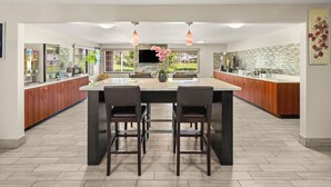 A modern kitchen with a central island, wooden cabinets, and pendant lighting.