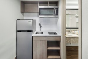 A compact kitchenette with a refrigerator, microwave, sink, and wooden cabinets. - Red Roof Inn & Suites Marysville (Marysville)