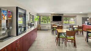 A modern kitchen with a coffee machine, a TV, and a dining area with wooden chairs and tables.
