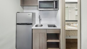 A compact kitchen with a built-in microwave, a refrigerator, a sink, and a countertop.