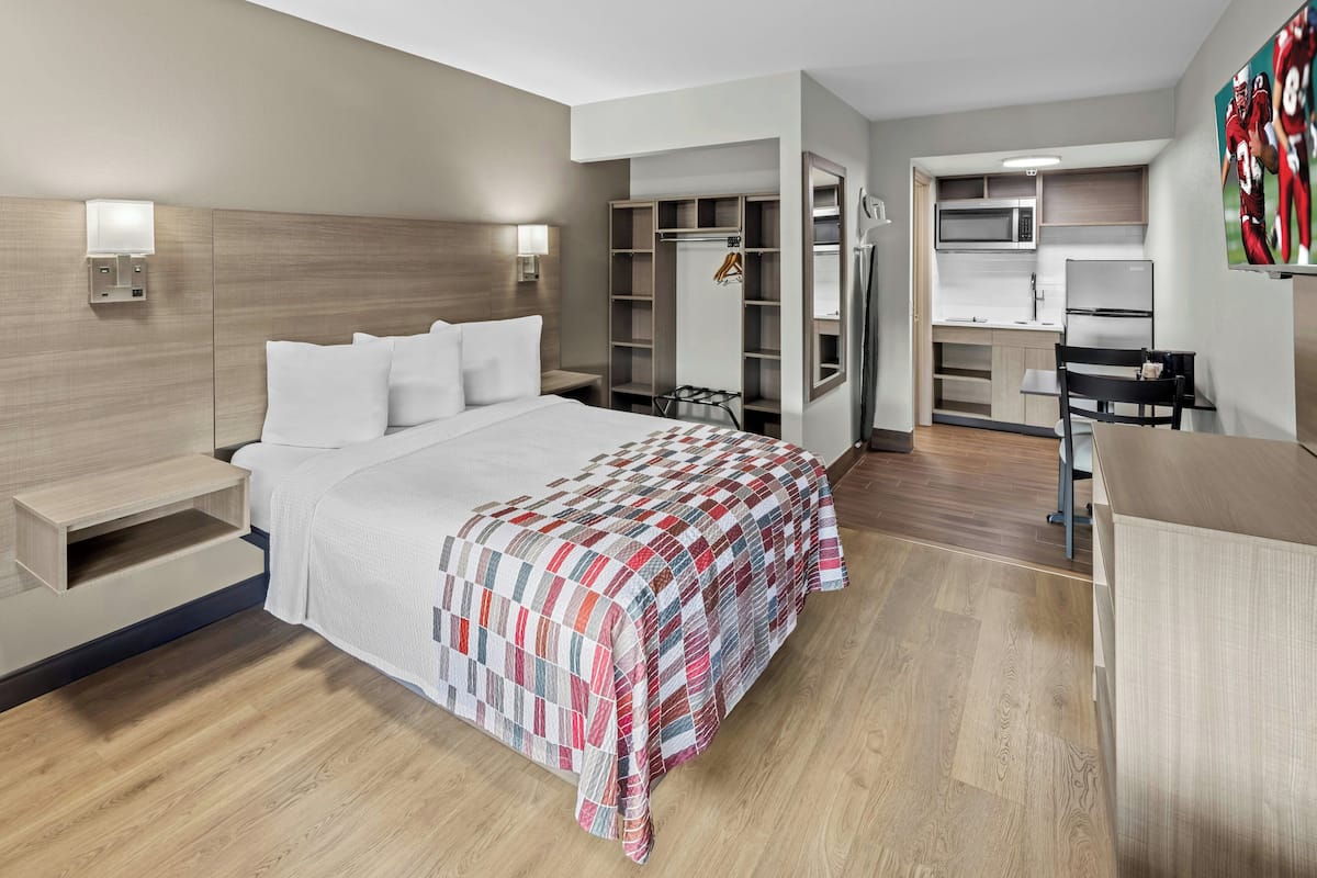 Une chambre d’hôtel comprenant un lit, des tables de chevet, une armoire, un bureau et une kitchenette.