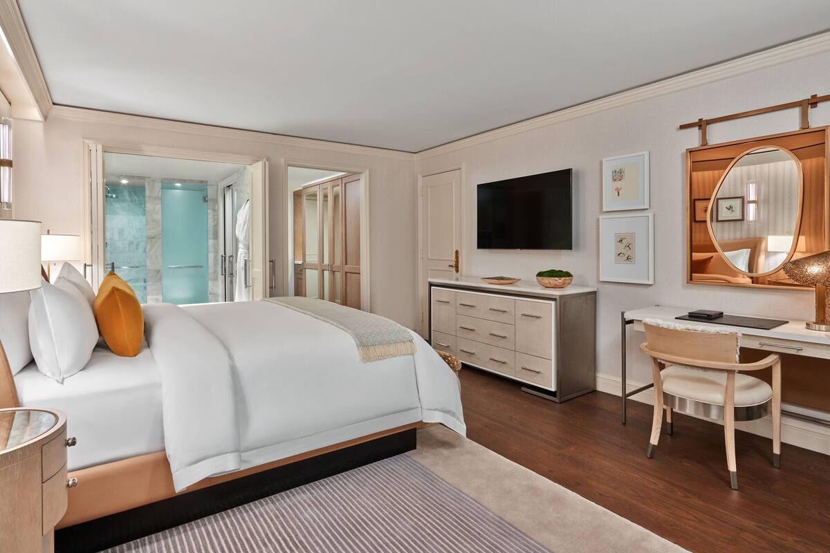 A modern bedroom with a large bed, a desk, and a TV.