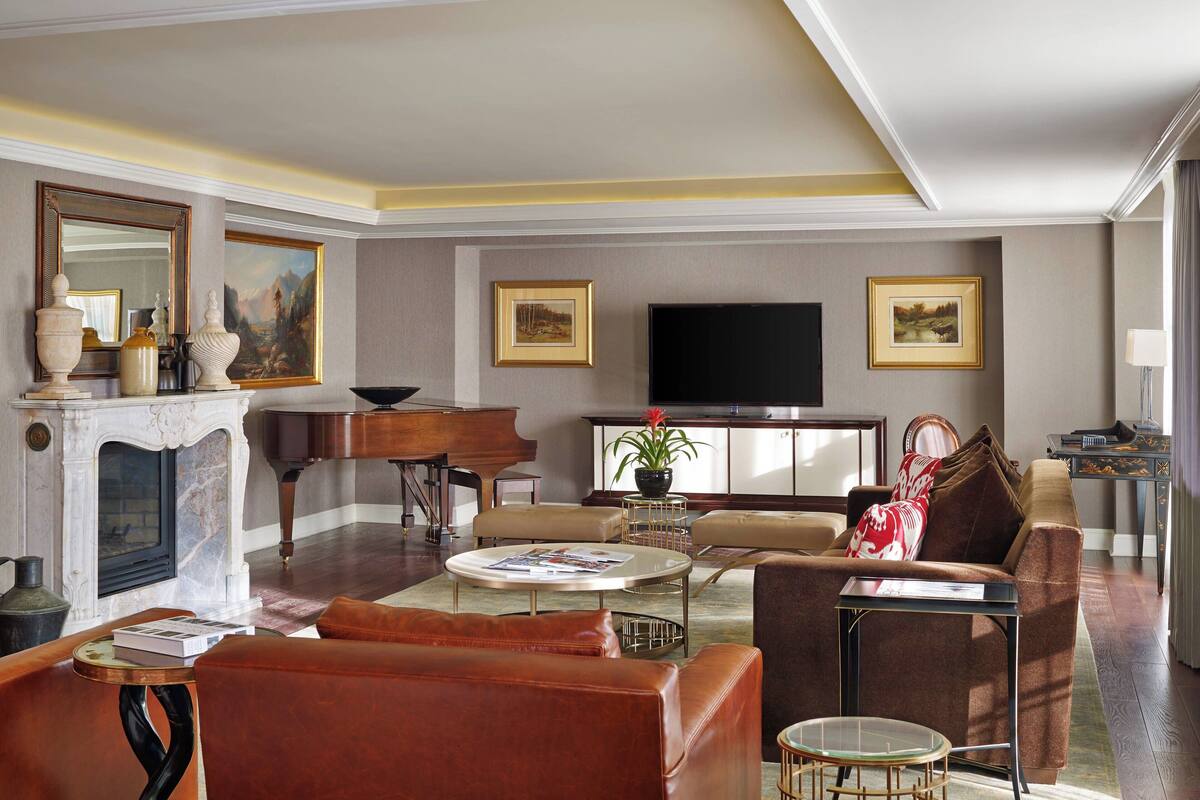 A spacious living room with a fireplace, a grand piano, a television, and comfortable seating.