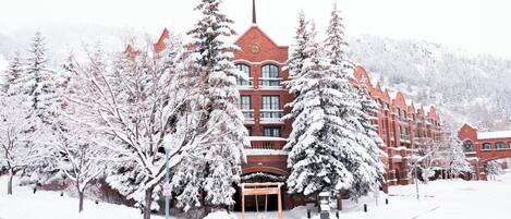 A snow-covered building with a prominent tower and multiple windows.
