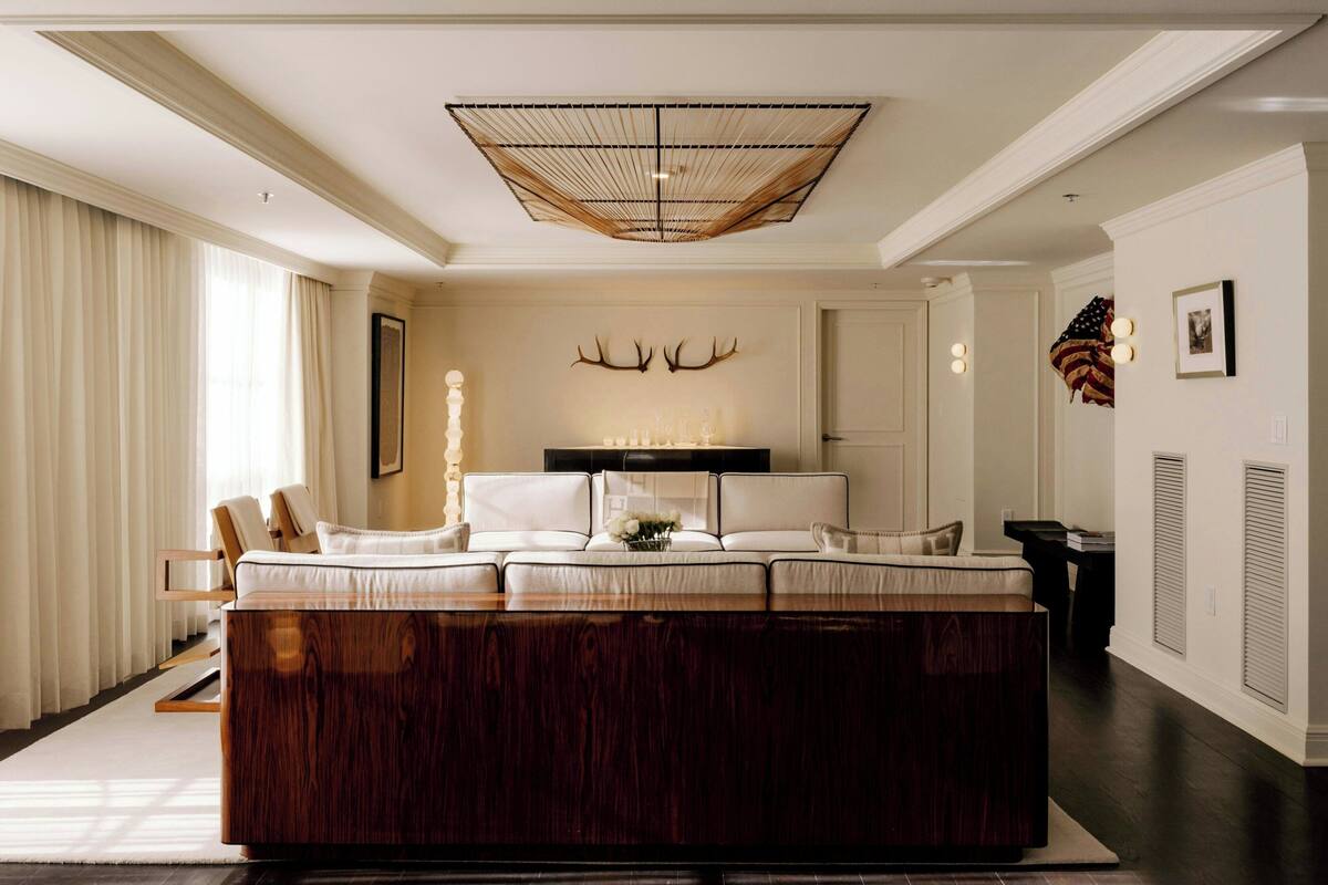 A spacious living room with a large wooden coffee table, a sofa set, and a decorative wall with antlers.