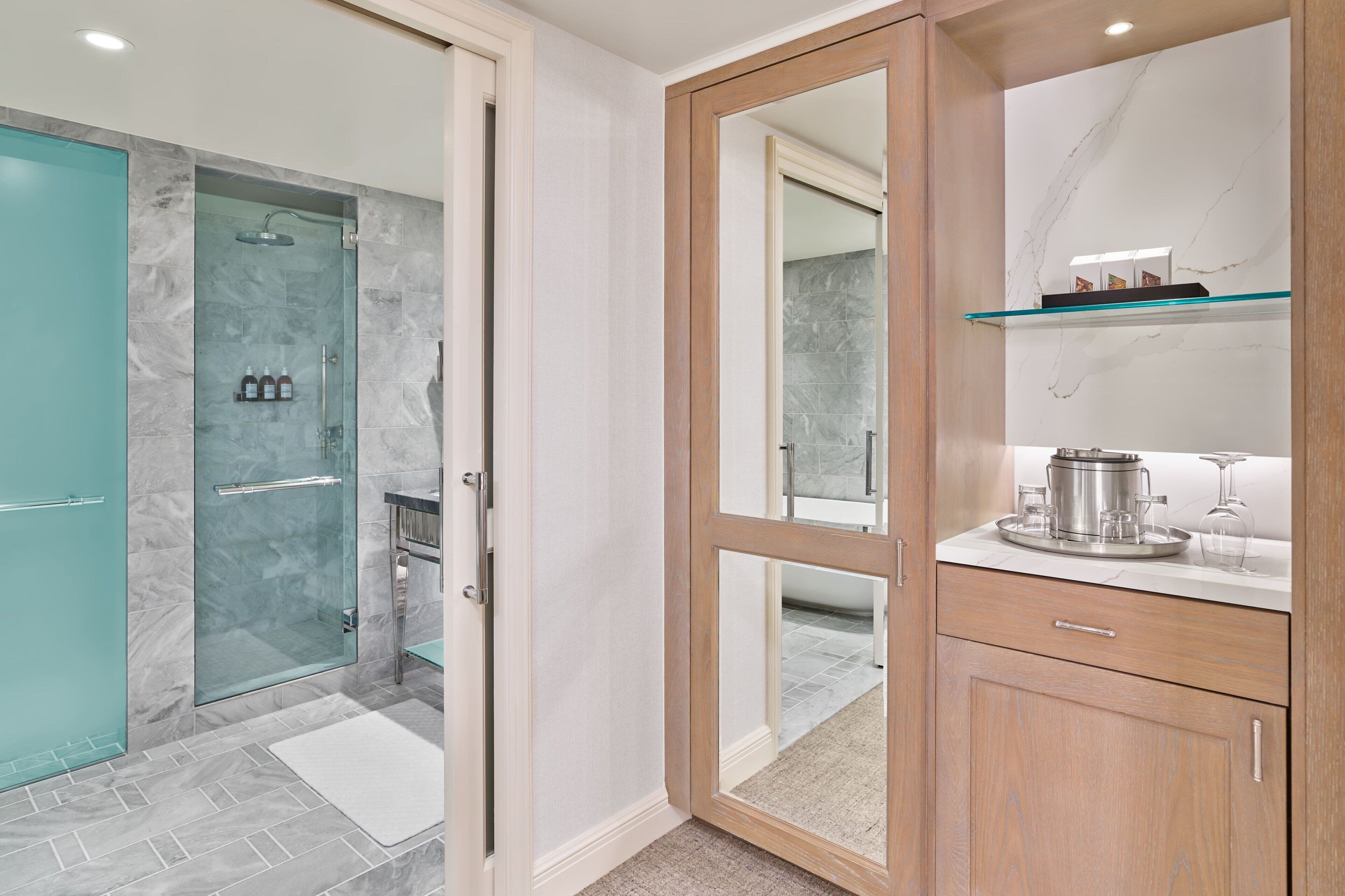 A modern bathroom with a glass shower enclosure, a wooden vanity with a marble countertop, and a mirror above the vanity.