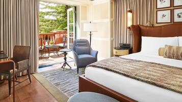 A hotel room with a large bed, a desk, a chair, and a view of the outdoors.