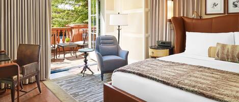 A hotel room with a large bed, a desk, a chair, and a view of the outdoors.