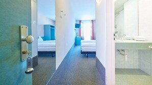Ein Hotelzimmer mit Bett, Schreibtisch und Bad mit Waschbecken und Spiegel.