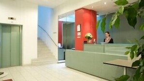 Ein Empfangsbereich mit einer Rezeption, einer Treppe und einer grünen Wand.
