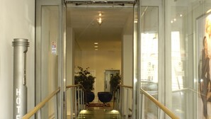 Eine Glasstiege führt zu einer Lobby, in der ein Schild mit der Aufschrift 'HOTEL CITY' zu sehen ist.