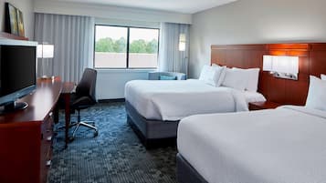 Quarto de hotel com duas camas, uma escrivaninha e televisão, e vista para o exterior.