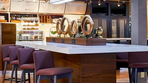 A modern bar area with a central island, bar stools, and a menu board in the background. - Sonesta Select Raleigh Durham Airport Morrisville (Morrisville)