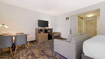 Ein Hotelzimmer mit Bett, Fernseher, Schreibtisch mit Stuhl, einer Mikrowelle und einer kleinen Sitzecke.