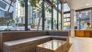 A modern interior with a sectional sofa, a glass coffee table, and large windows offering a view of the cityscape. - Best Western Plus Bayside Inn (San Diego)