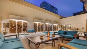 A poolside area with wicker furniture, a pool, and a building in the background. - Best Western Plus Bayside Inn (San Diego)