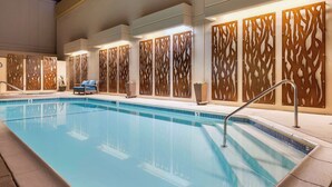 A swimming pool with a tiled edge, a blue lounge chair, and decorative wooden panels. - Best Western Plus Bayside Inn (San Diego)
