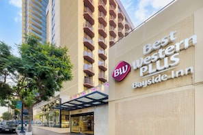 Un hôtel affichant une enseigne indiquant « Best Western PLUS Bayside Inn », un bâtiment moderne doté de balcons et d’une façade en verre.