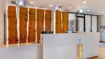 A reception desk with a wooden backdrop, a digital screen, and a sign indicating garage access.