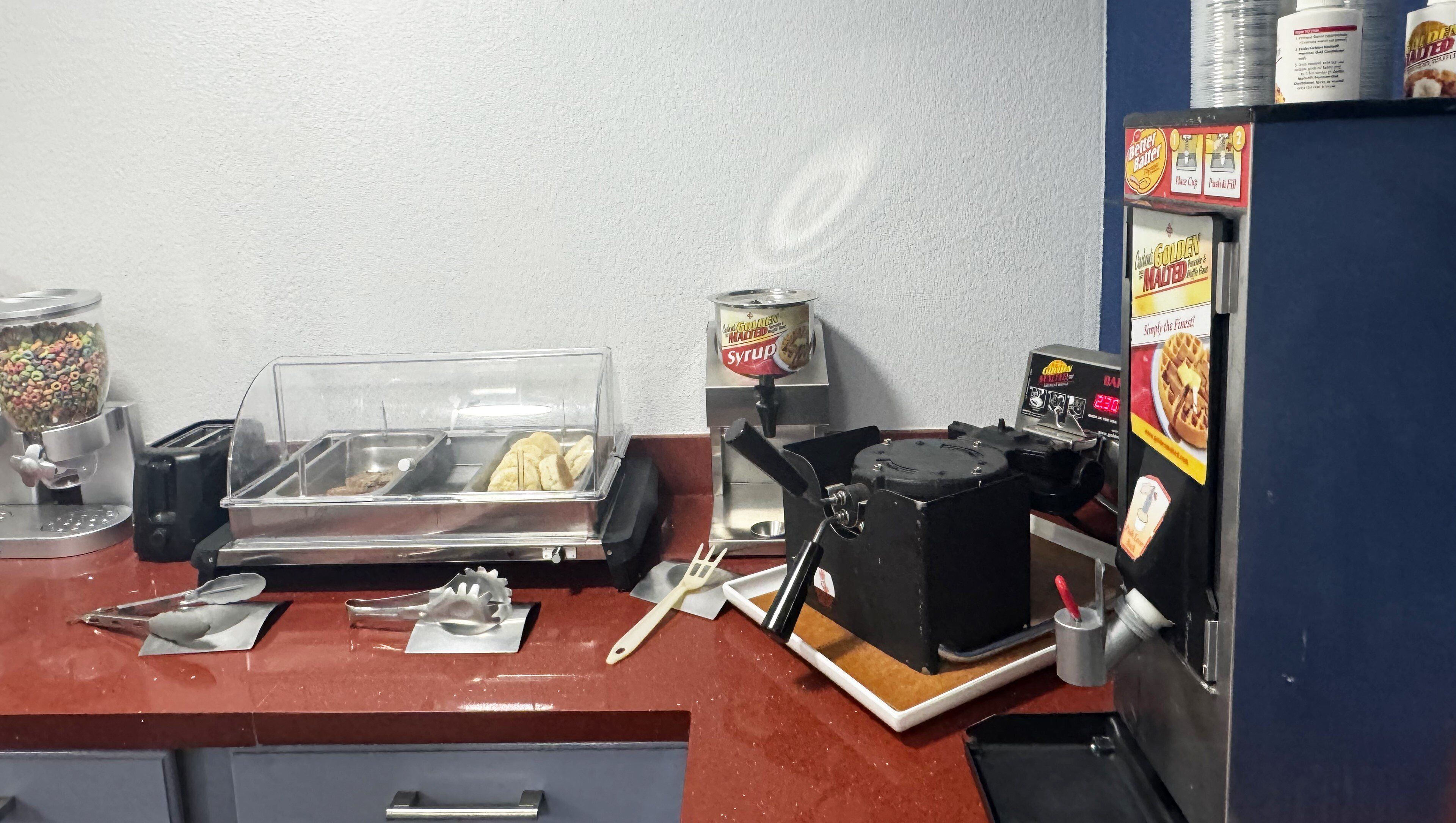 A breakfast station with cereal, syrup, and waffle makers.