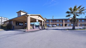 Een motel met een overdekte parkeerplaats, meerdere verdiepingen en een palmboom.