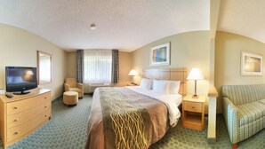 A hotel room with a bed, a TV, a chair, a desk, and a lamp.