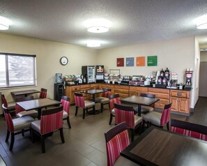 A restaurant with tables and chairs, a refrigerator, a coffee machine, and a clock on the wall.