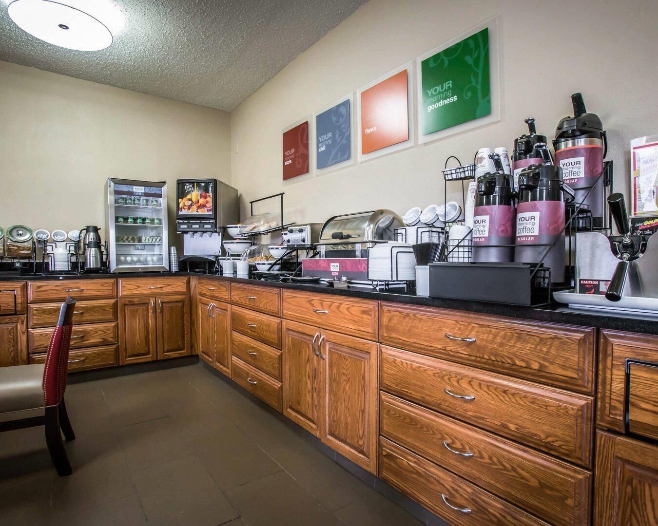 A kitchen area with wooden cabinets, a coffee machine, a refrigerator, and a microwave.