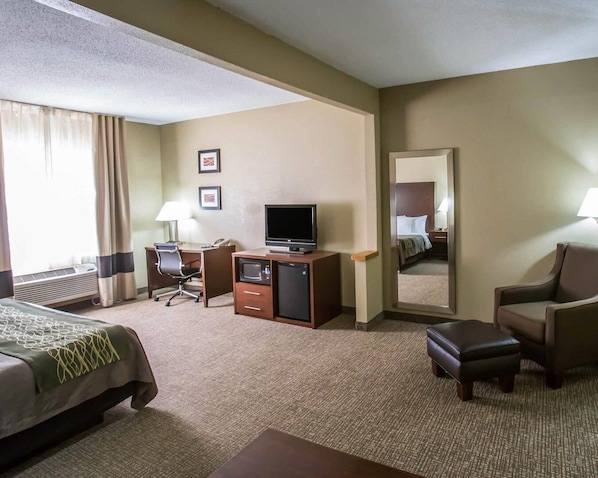 A hotel room with a bed, desk, chair, television, and a mirror.