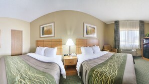 A hotel room with two beds, a nightstand, a lamp, a chair, an air conditioning unit, and a television.