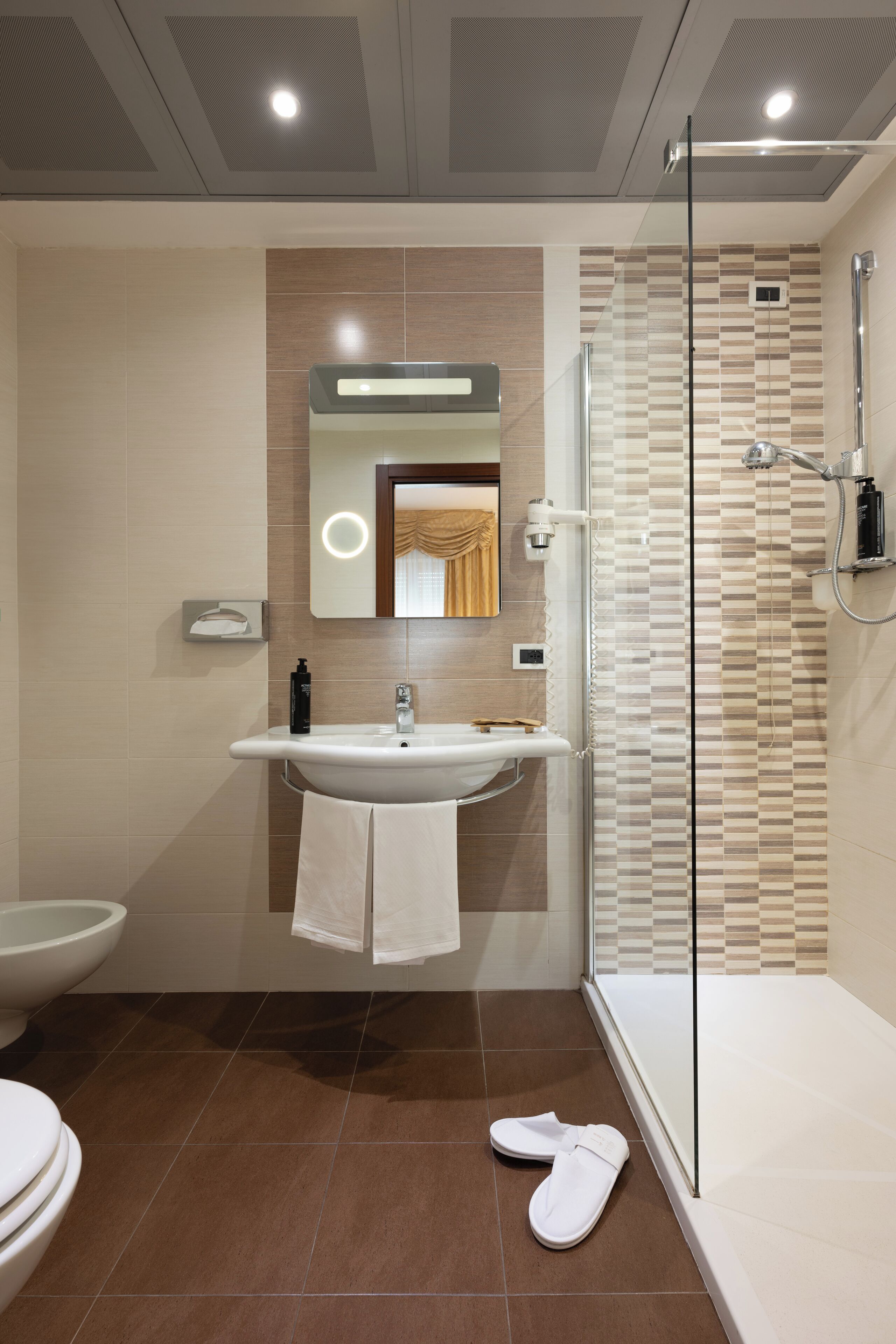 Ein modernes Badezimmer mit einer Glasdusche, einem weißen Waschbecken und einer Toilette.