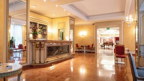A spacious lobby with a marble floor, a bar area with a large mirror, and red chairs.