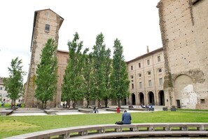 A courtyard with a historic building featuring arched windows and a tower.
