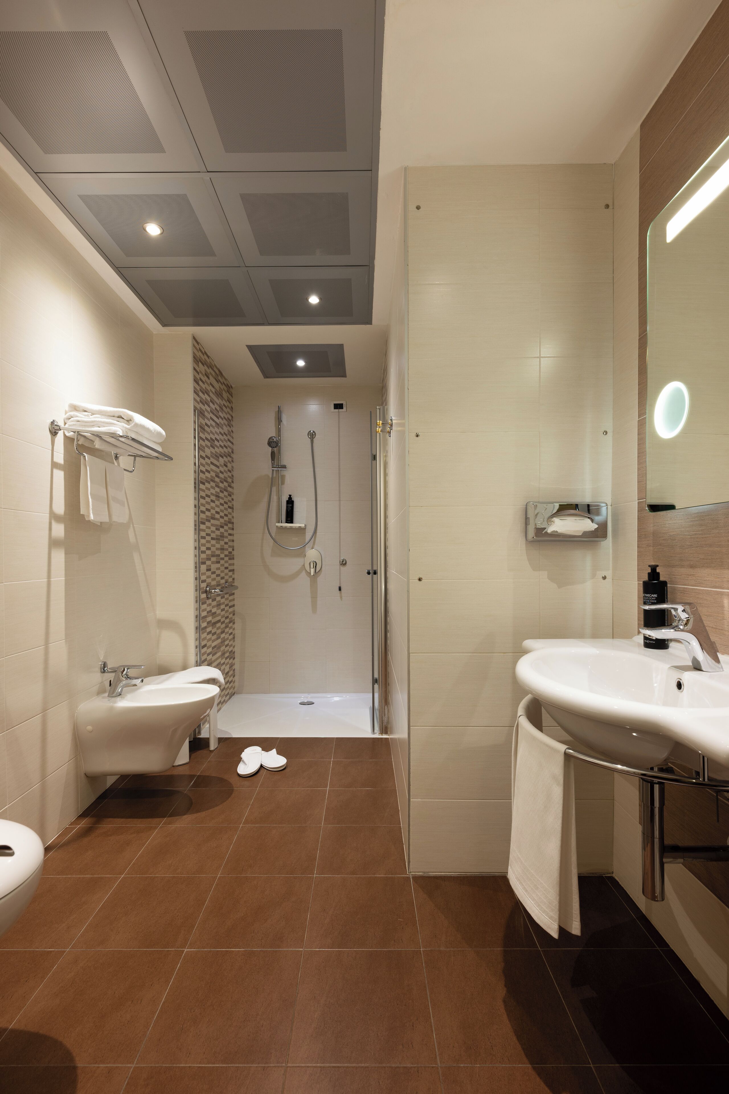 A modern bathroom with a shower, two sinks, and a toilet.