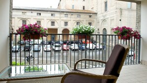 A balcony with wicker chairs, a glass table, and flower pots.