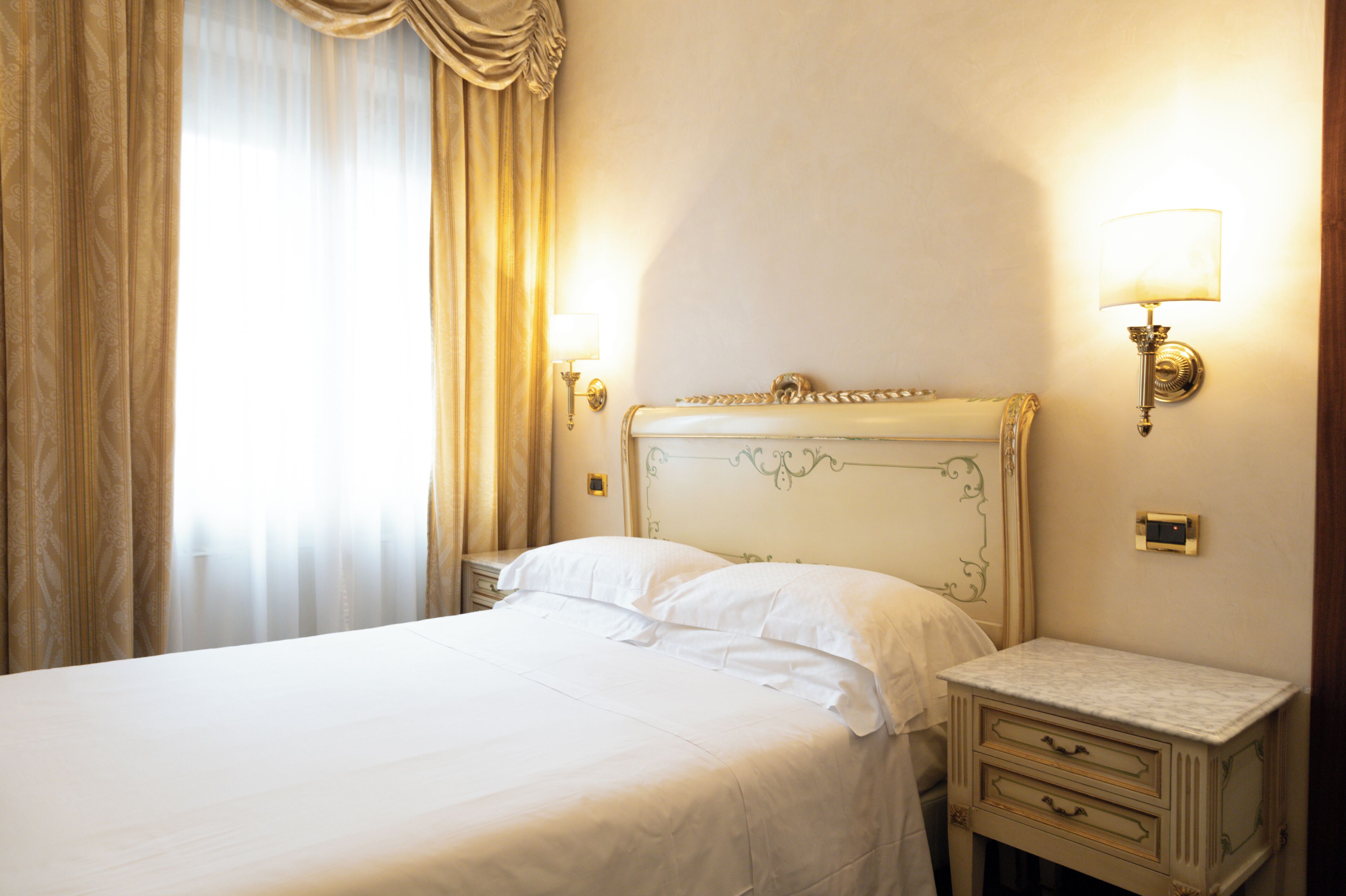 Una cama bien hecha con sábanas blancas en una habitación de hotel.