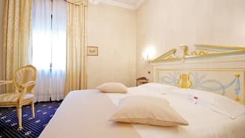 A hotel room with a large bed, a chair, a desk, and a chandelier.