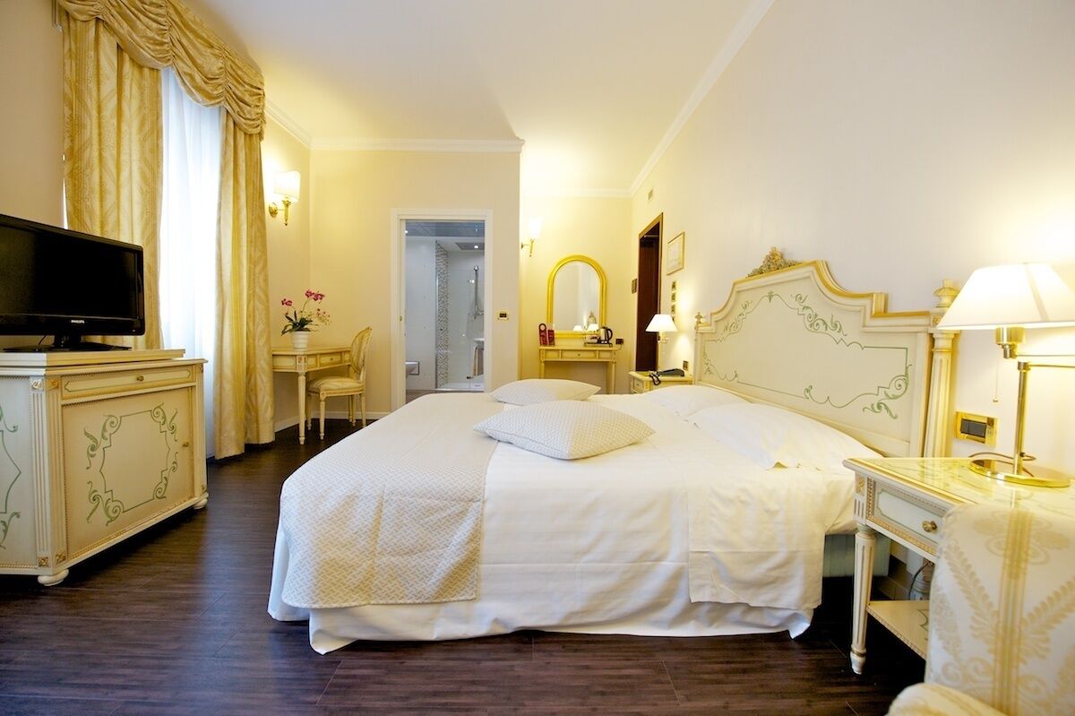 Habitación de hotel con una cama grande, televisión, escritorio y silla.