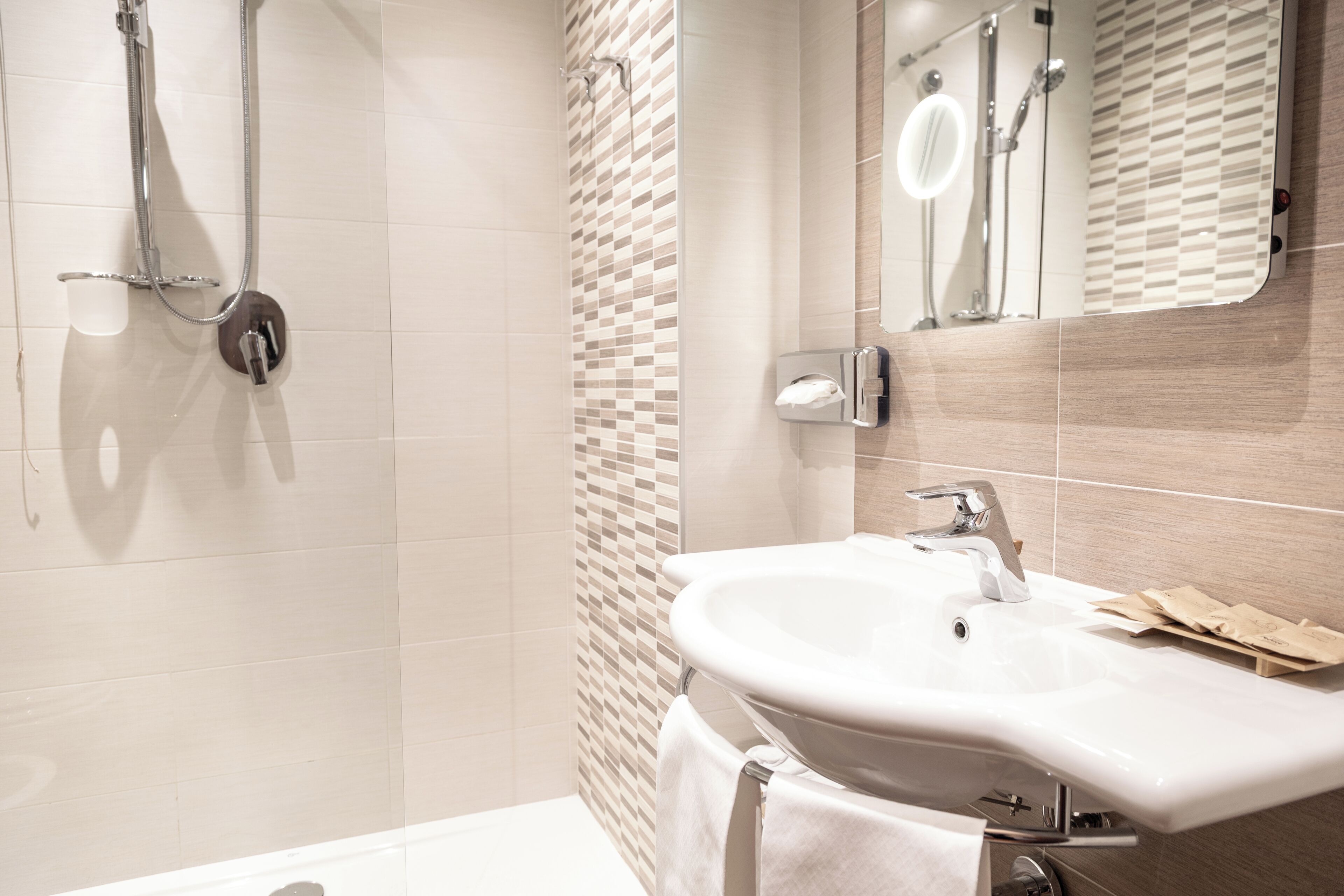 Een moderne badkamer met een wit wastafelmeubel, een handdoekhouder en een douchehoek.