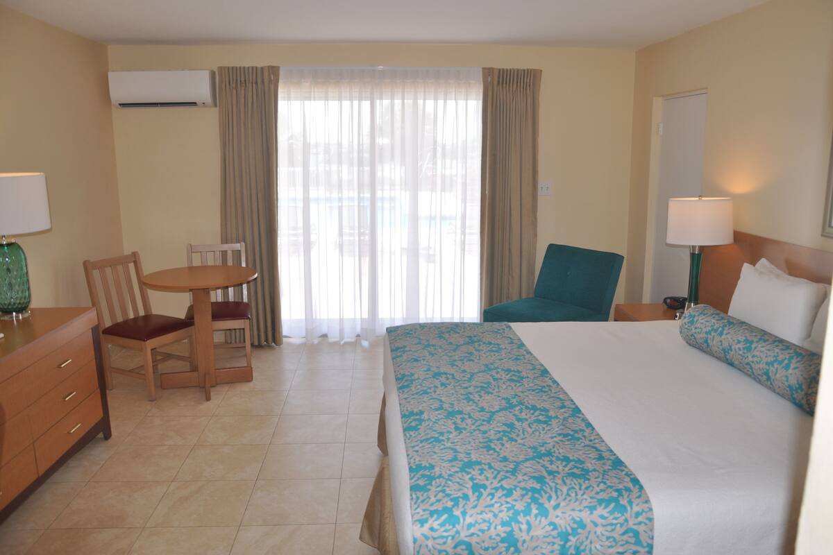 A hotel room with a bed, a desk, a chair, and a window with curtains.