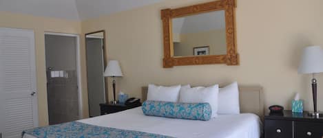 A hotel room with a bed, a nightstand, a dresser, a mirror, and a door.