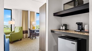 A compact hotel room with a kitchenette, a dining area with a view, and a green armchair. - Comfort Inn Gold Coast (Ocean City)
