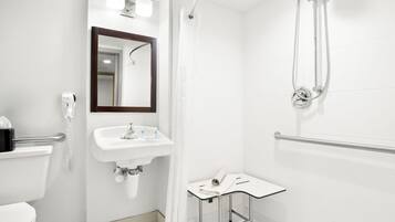 Un baño moderno con inodoro, lavamanos, espejo, ducha y una mesita con una toalla.