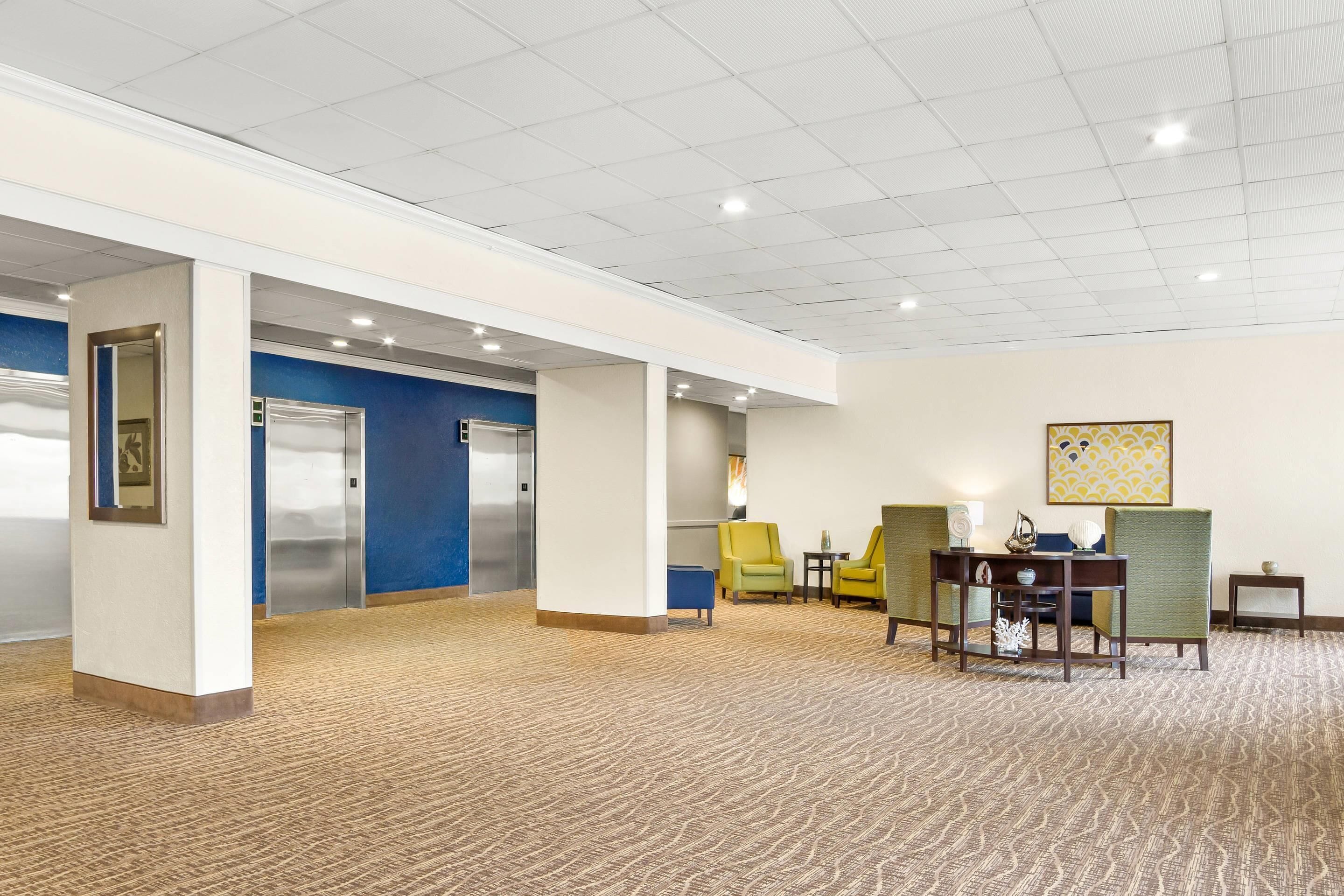 Un hall d’entrée spacieux, doté d’un tapis à motifs, d’un comptoir de réception et de plusieurs espaces où s’asseoir.