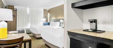 A hotel room with a bed, bedside table, lamp, and a microwave above the counter.