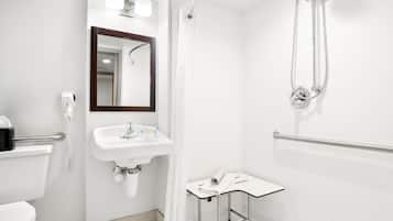 A modern bathroom with a toilet, sink, mirror, shower, and a small table with a towel.