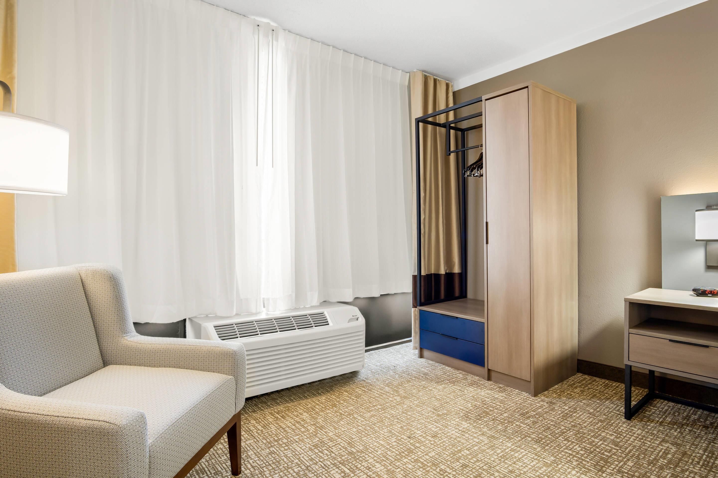 A hotel room with a sofa, a desk, a wardrobe, and a radiator.