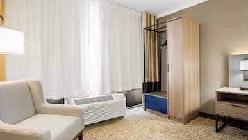 A hotel room with a sofa, a desk, a wardrobe, and a radiator.
