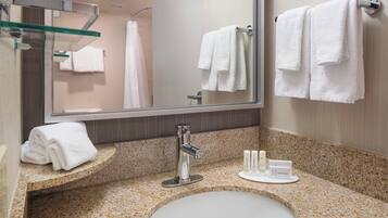 A bathroom with a sink, mirror, towel rack, and toiletries.